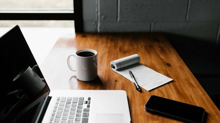 macbook pro, white ceramic mug and white note book