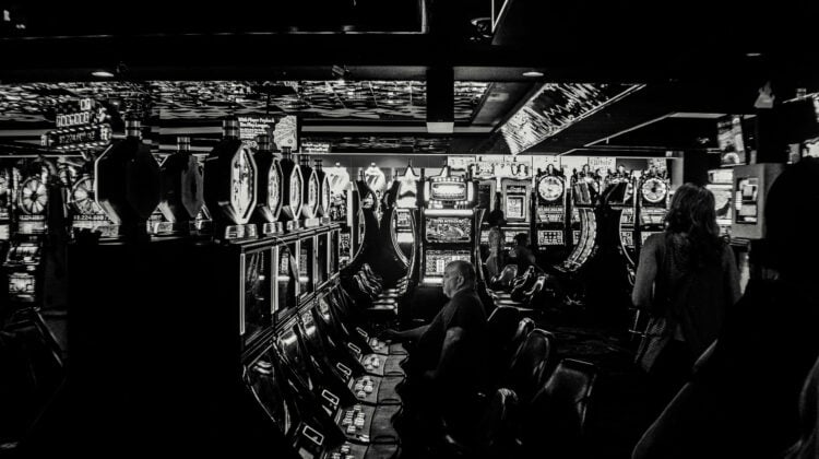 greyscale photo of man playing slot machine